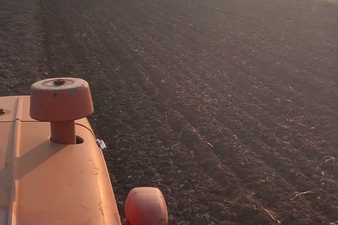 Il campo arato al tramonto visto dal posto di guida del trattore